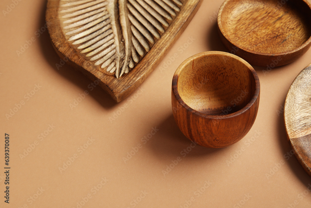 Different wooden tableware on beige background, closeup