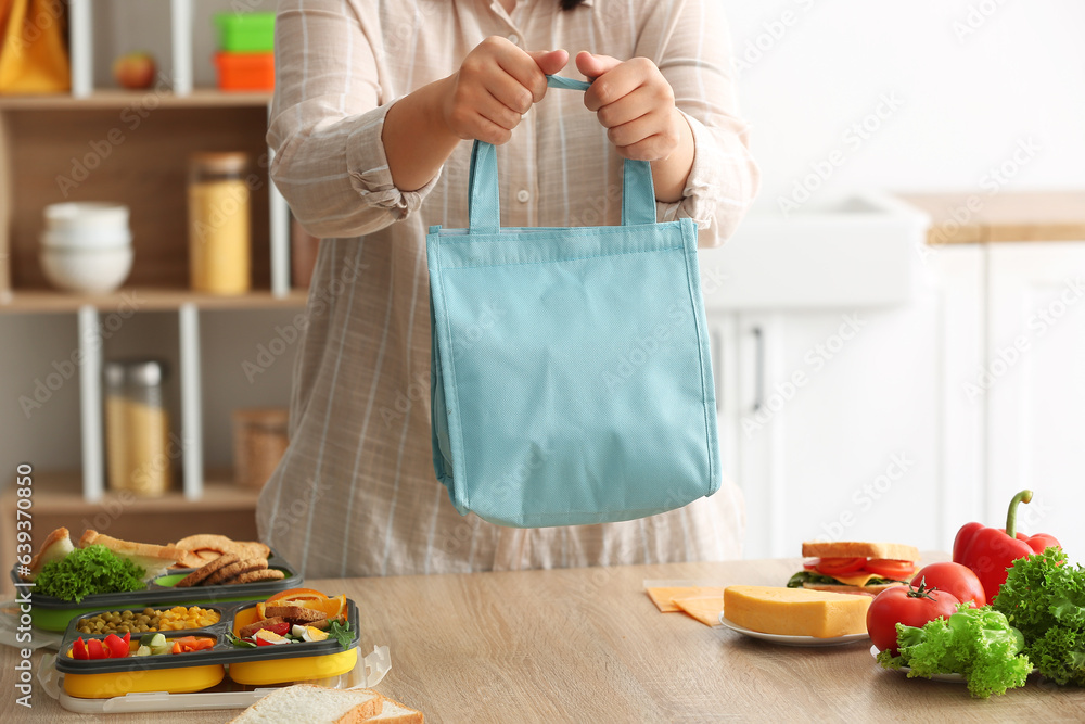 Mother with lunch box bag for school in kitchen