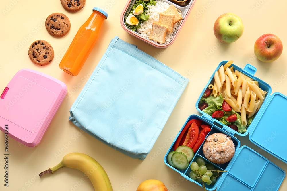 Bag, lunchboxes with delicious food and bottle of juice on yellow background