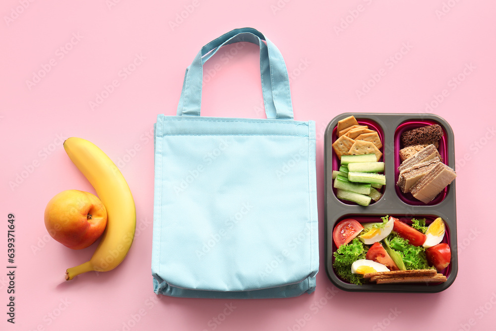 Bag, lunchbox with delicious food and fruits on pink background