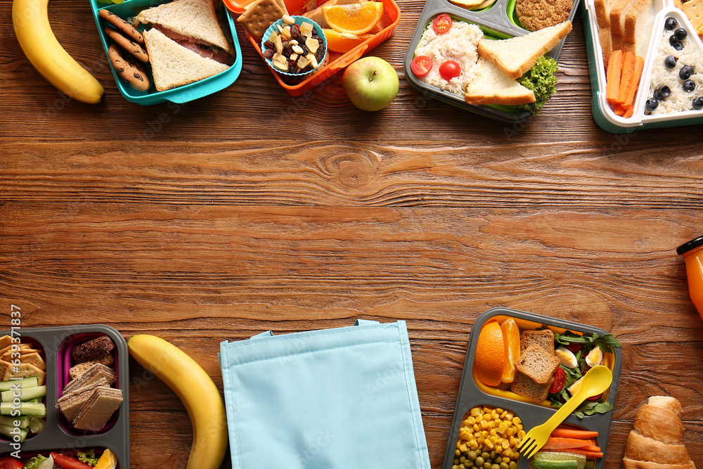 Bag, lunchboxes with different delicious food and fruits on brown wooden background