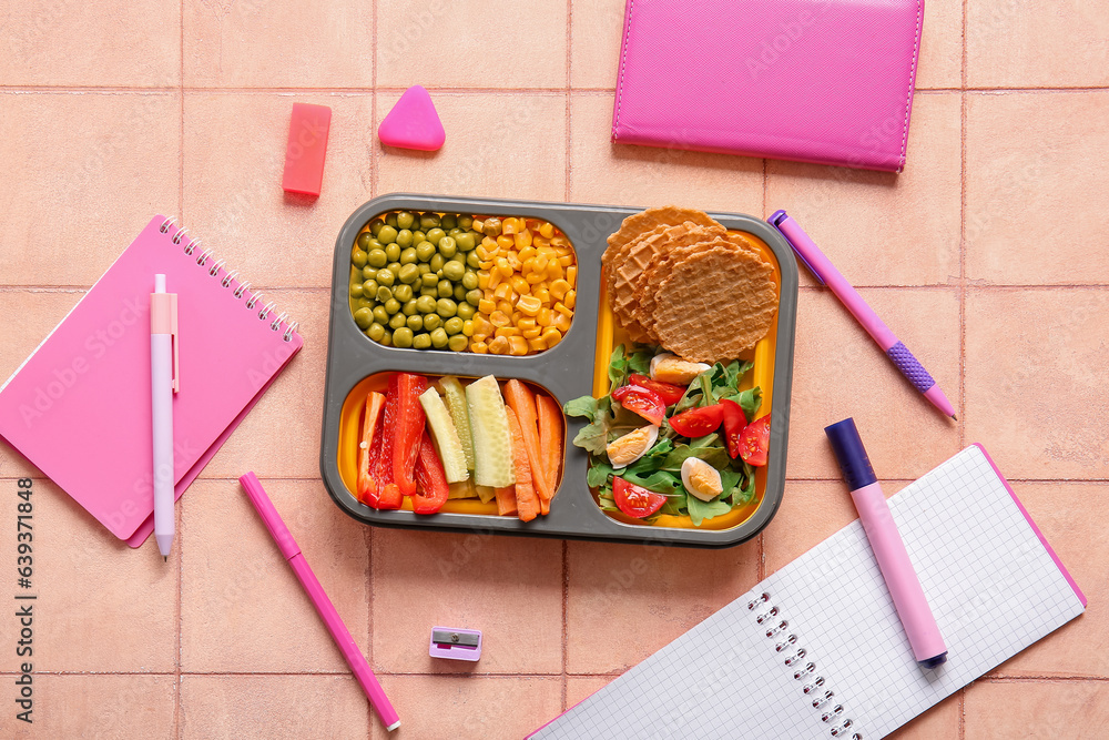 Lunchbox with delicious food and different stationery on orange tile background