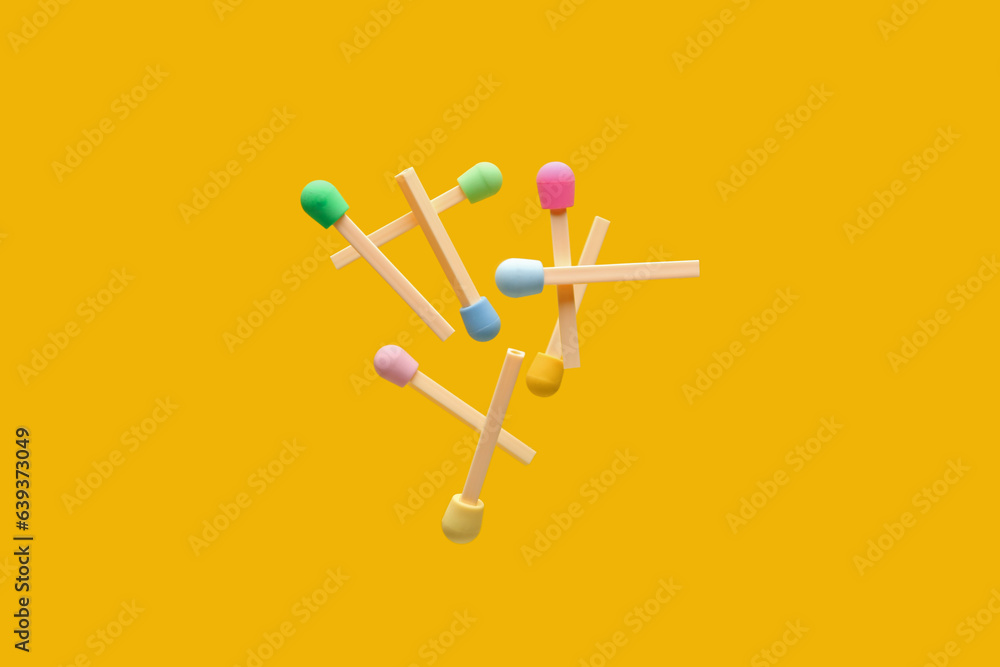 Erasers in shape of colorful matches flying on yellow background