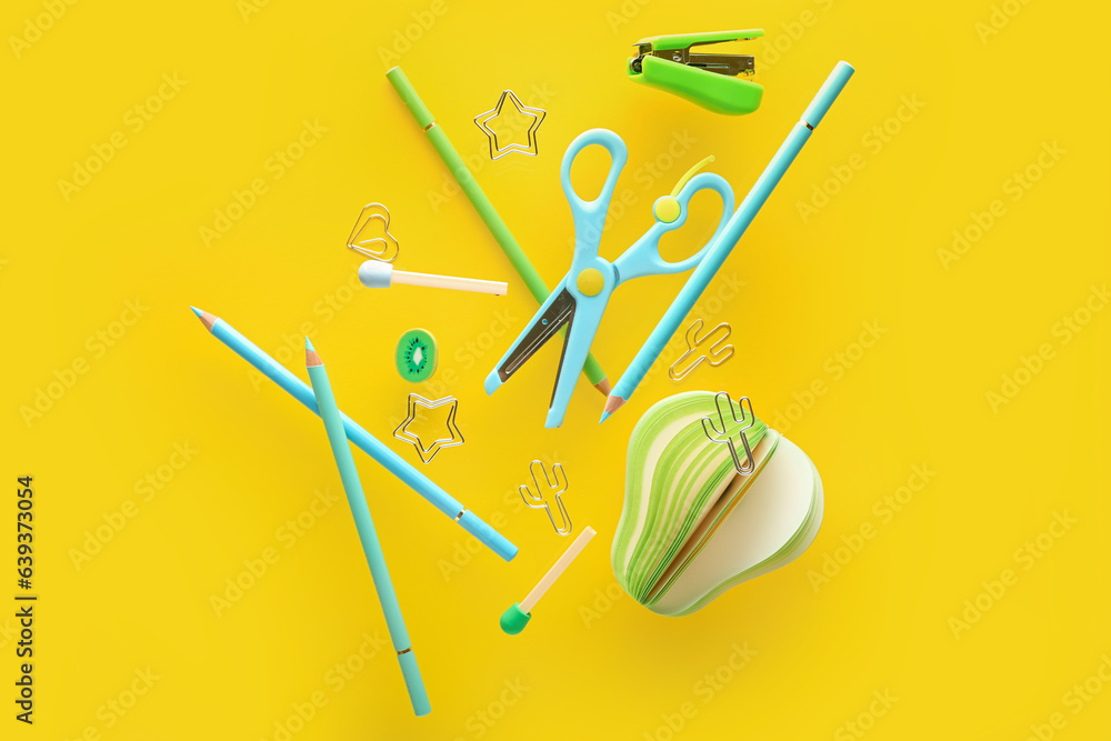 Flying colorful stationery on yellow background