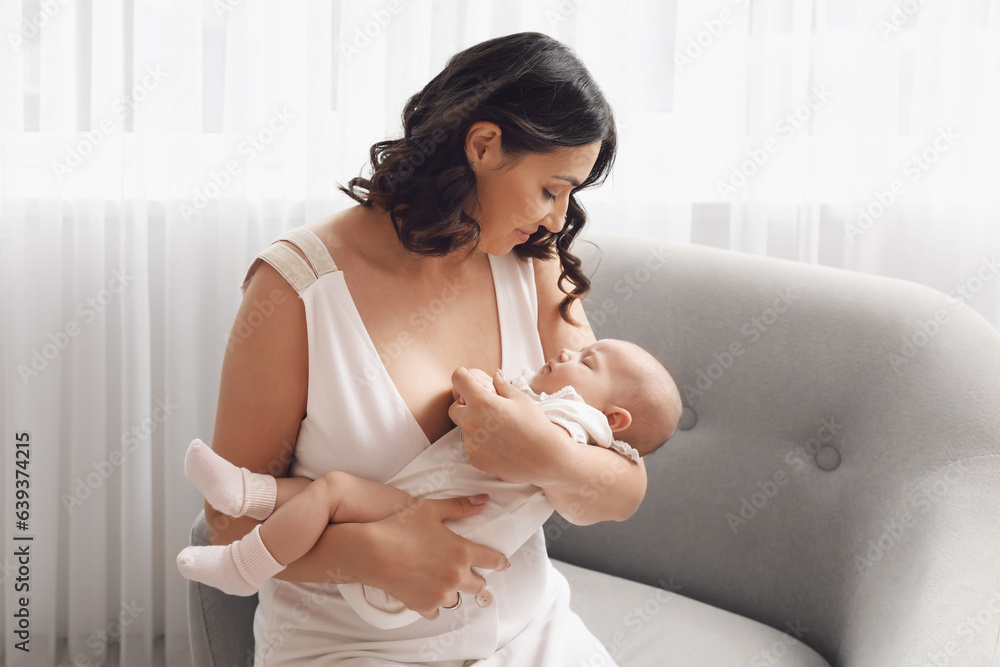 Young woman with her baby sitting in armchair at home