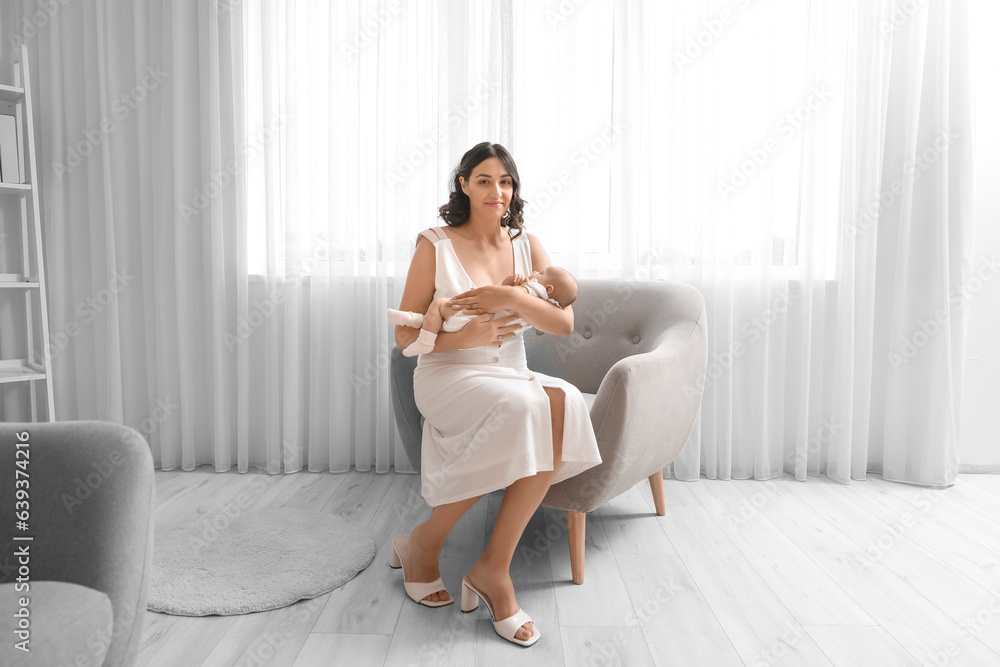 Young woman with her baby sitting in armchair at home