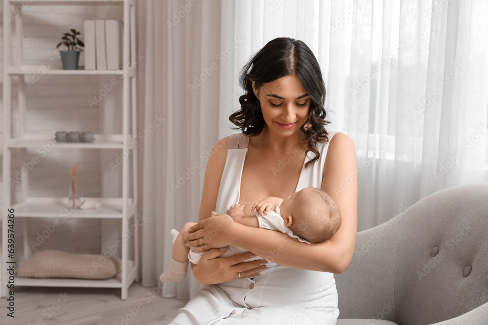 Young woman with her baby sitting in armchair at home