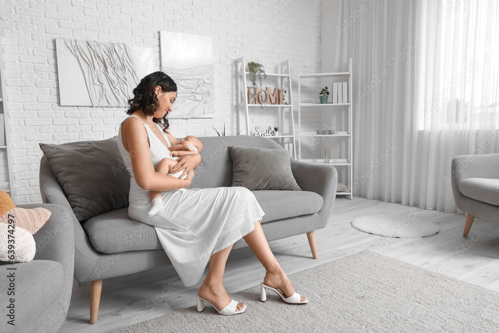 Young woman with her baby sitting on sofa at home