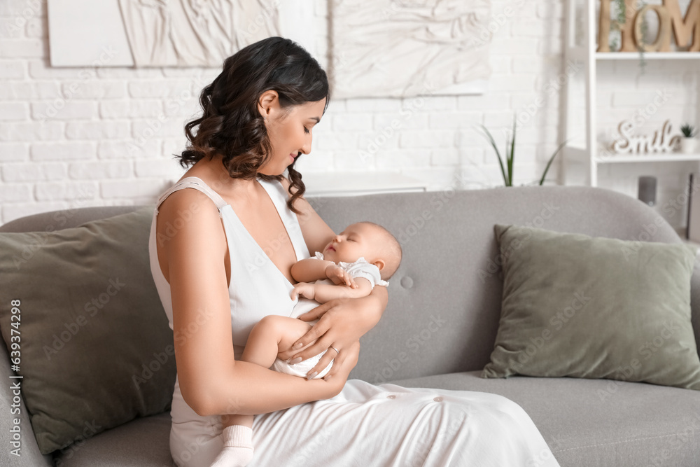 Young woman with her baby sitting on sofa at home