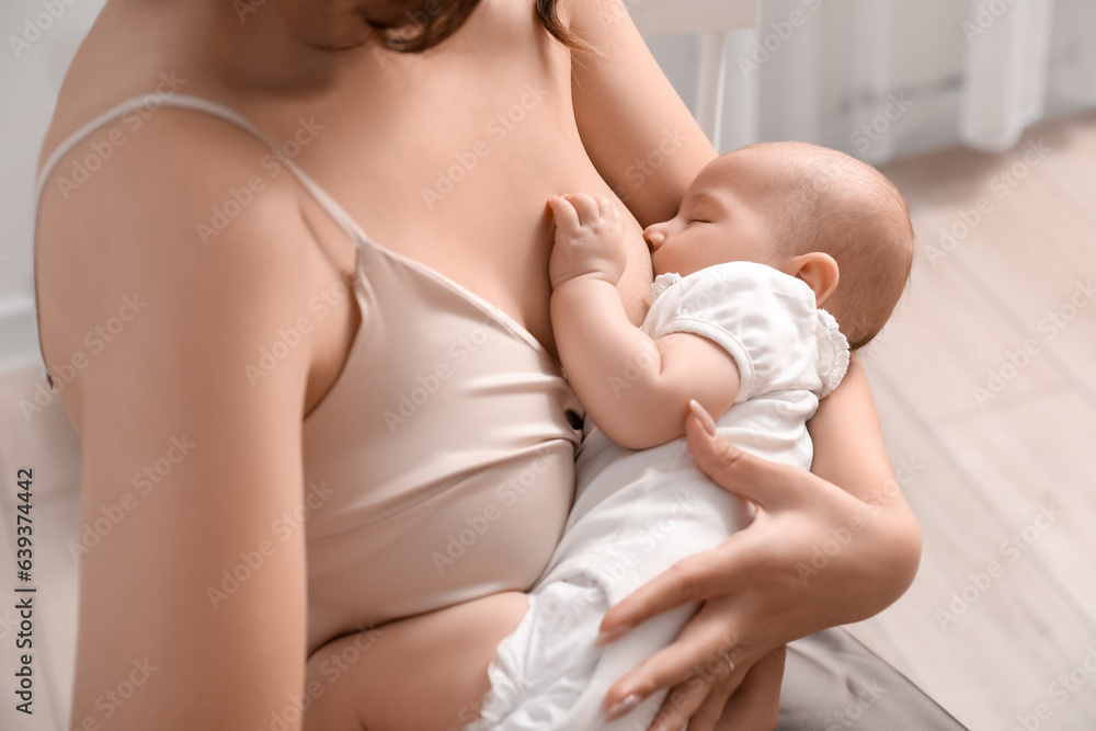 Young woman breastfeeding her baby in bedroom, closeup