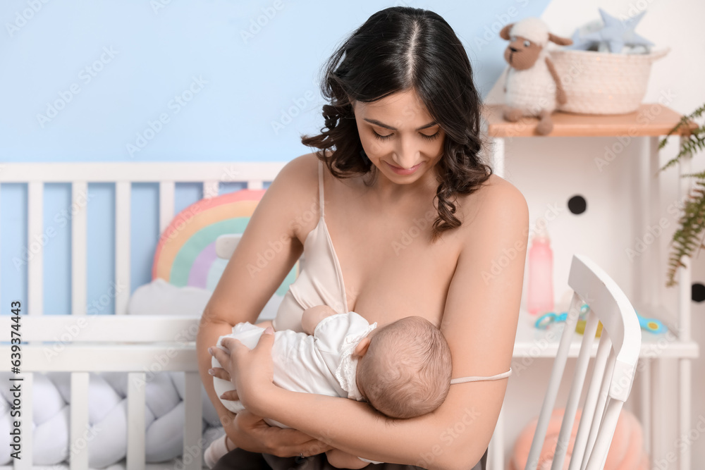 Young woman breastfeeding her baby in bedroom