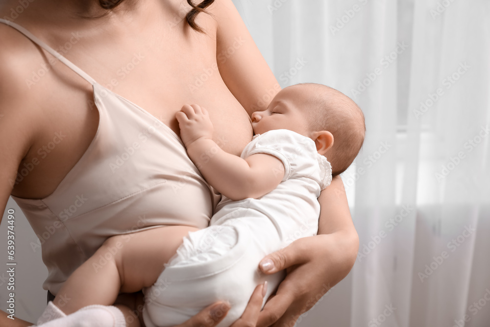 Young woman breastfeeding her baby in bedroom, closeup