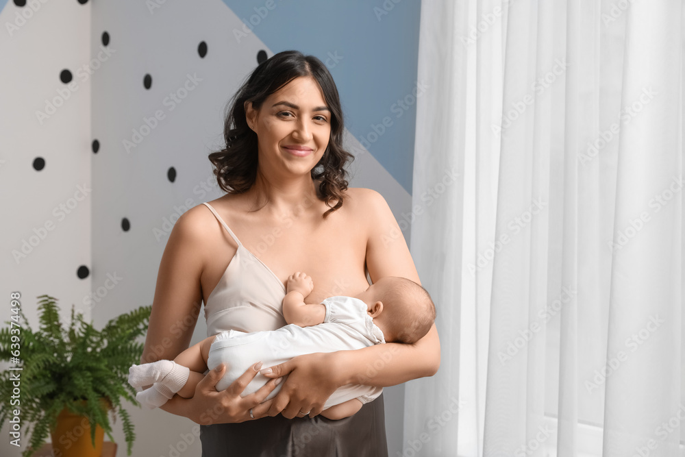 Young woman breastfeeding her baby in bedroom