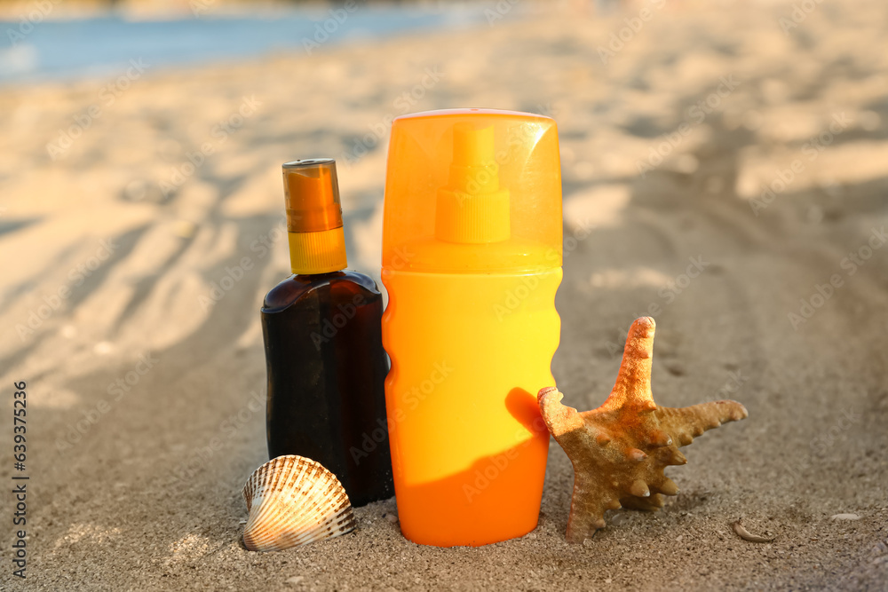 Bottles of sunscreen cream with starfish on sand at beach