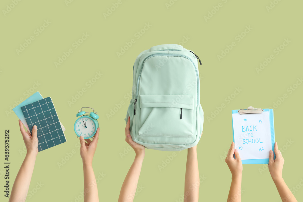 Female hands holding backpack, alarm clock and notebooks with text BACK TO SCHOOL on green backgroun