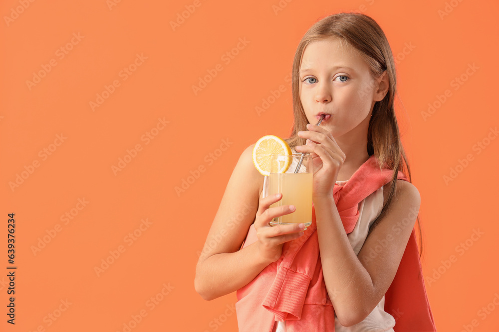 Little girl drinking fresh citrus juice on orange background