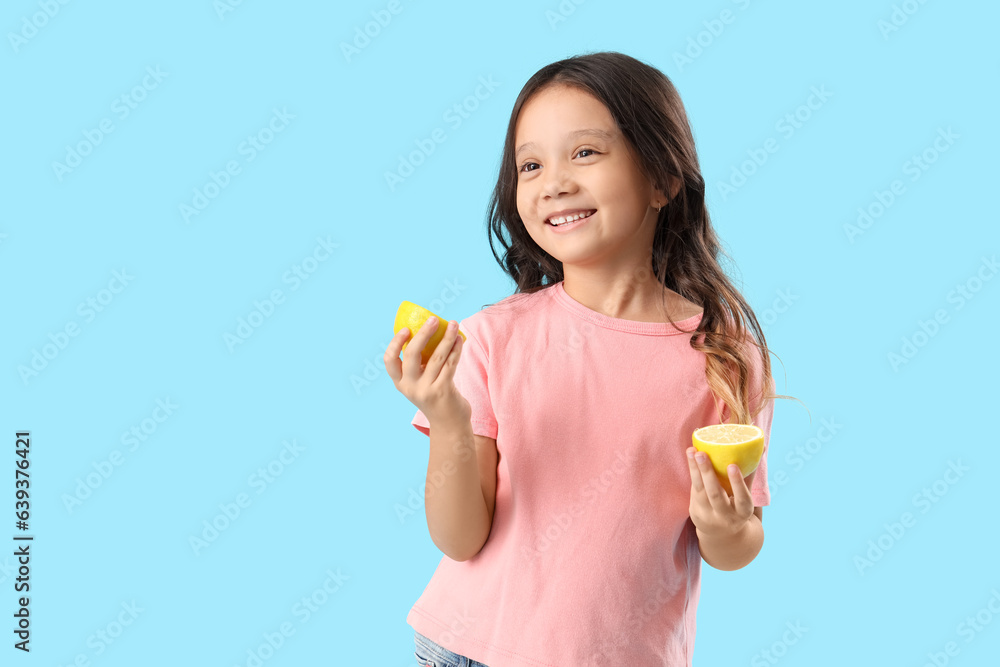 Little Asian girl with slices of fresh lemon on blue background