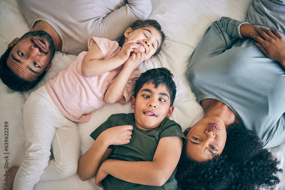 Top view, face and funny family in bed at home together, bonding to relax or having fun. Portrait, l