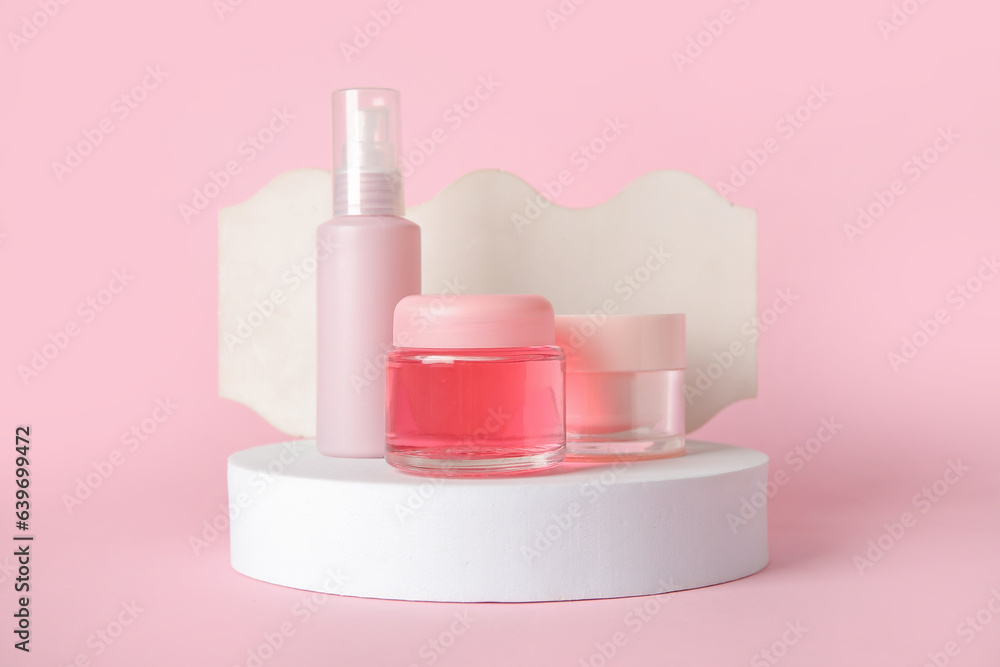 Composition with cosmetic products and podiums on pink background