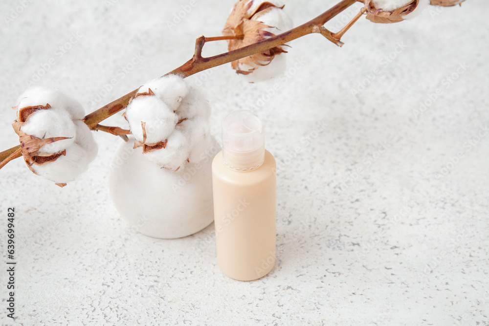 Bottle of cosmetic product, plaster podium and cotton branch on light background