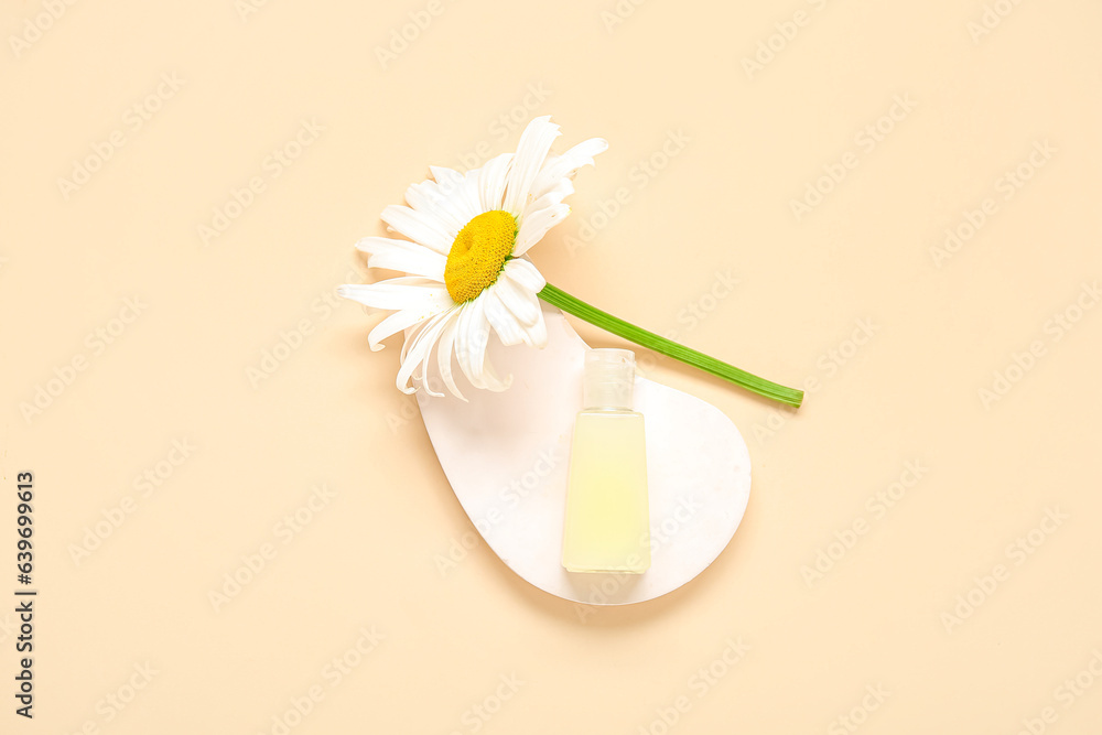 Plaster podium with bottle of cosmetic product and chamomile flower on color background