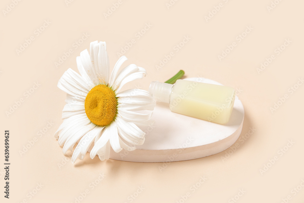 Plaster podium with bottle of cosmetic product and chamomile flower on color background