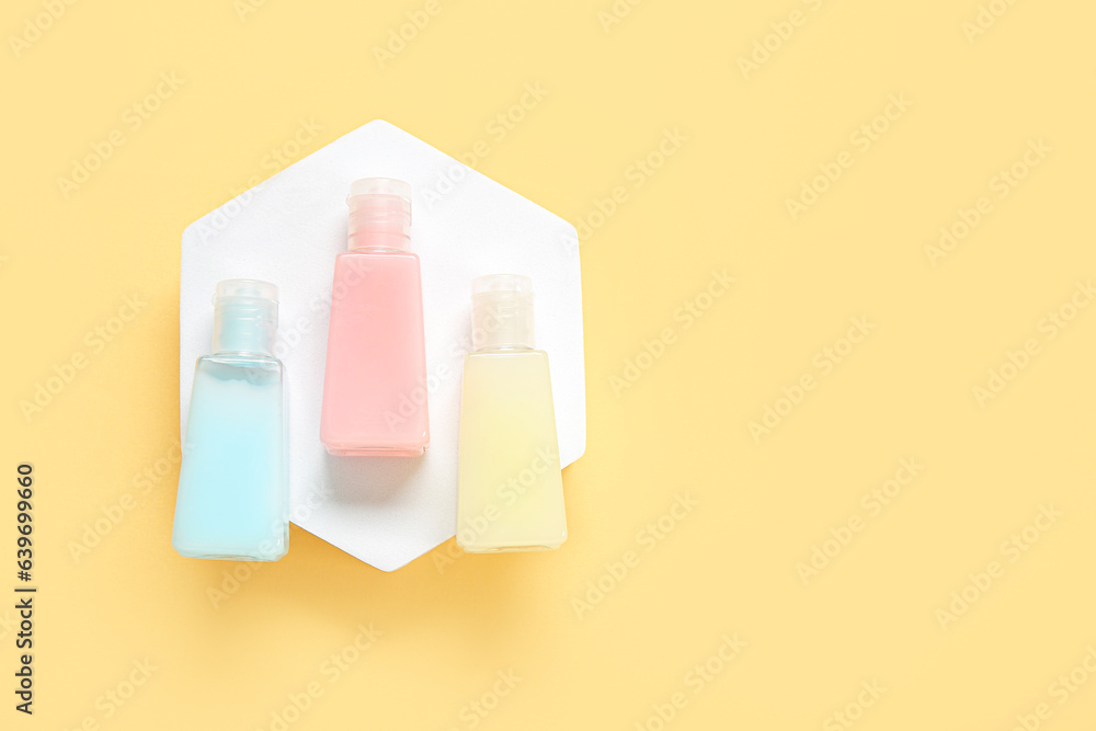 Plaster podium with bottles of cosmetic products on color background