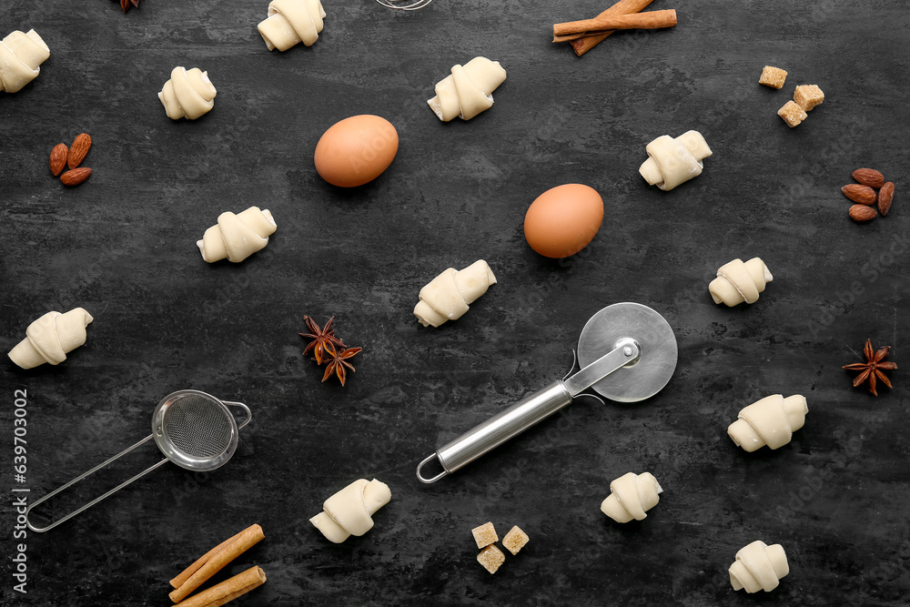 Composition with raw croissants, ingredients and utensils on dark background