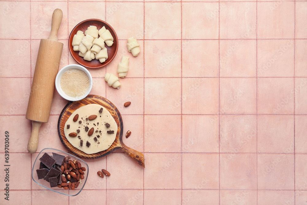 Composition with raw croissants, ingredients and rolling pin on color tile background