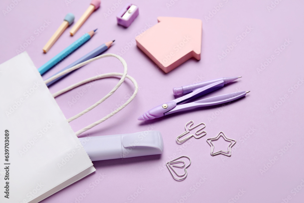 Composition with paper bag and different stationery on lilac background