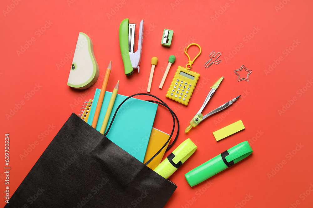 Paper bag with colorful stationery on red background