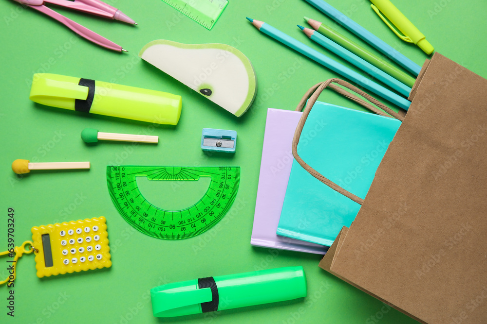 Composition with paper bag and different stationery on green background