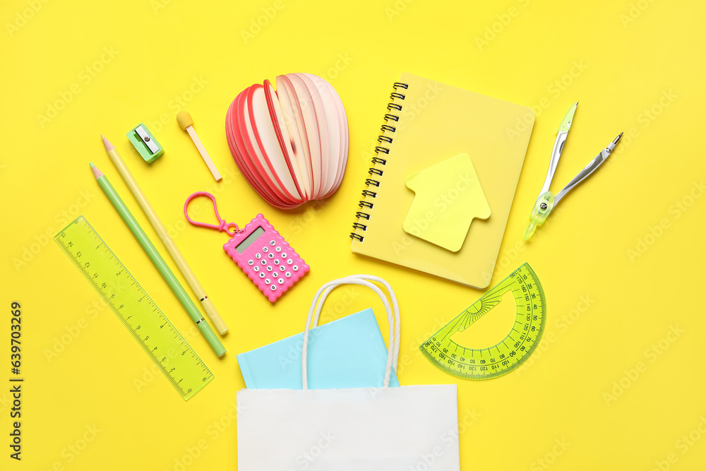 Composition with paper bag and different stationery on yellow background