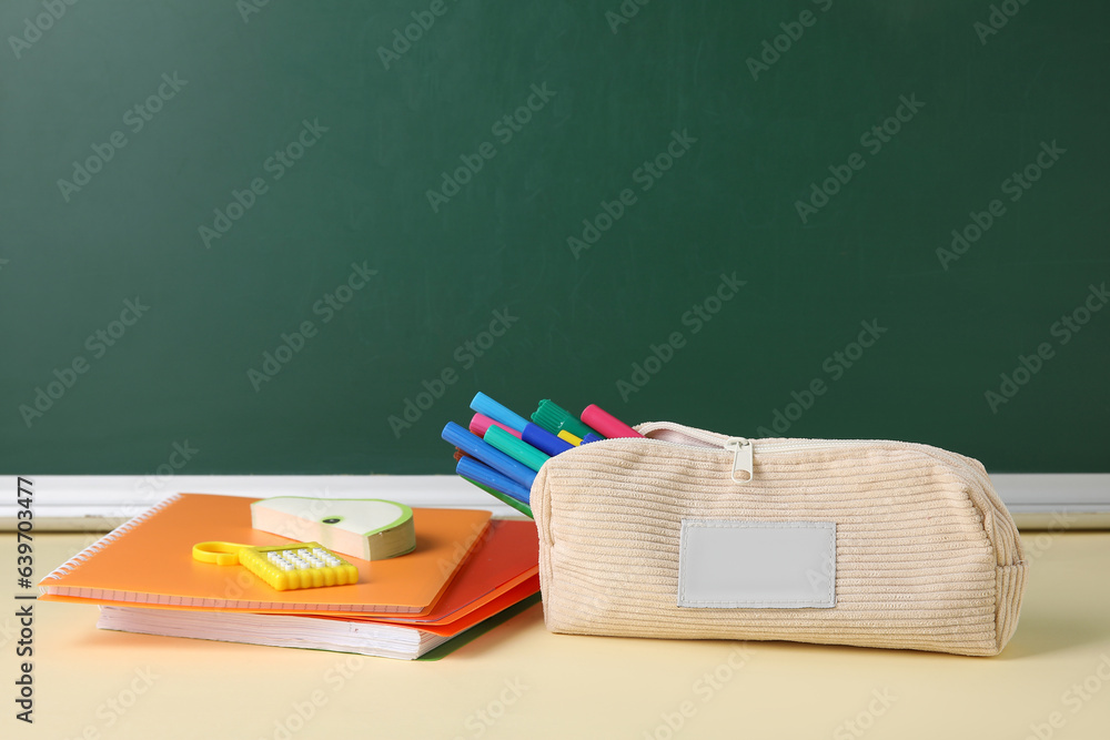 Different school stationery on table near blackboard