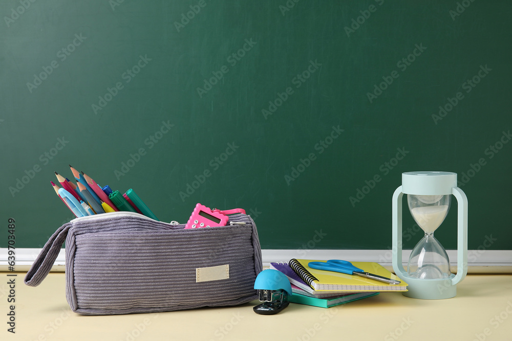 Different school stationery on table near blackboard