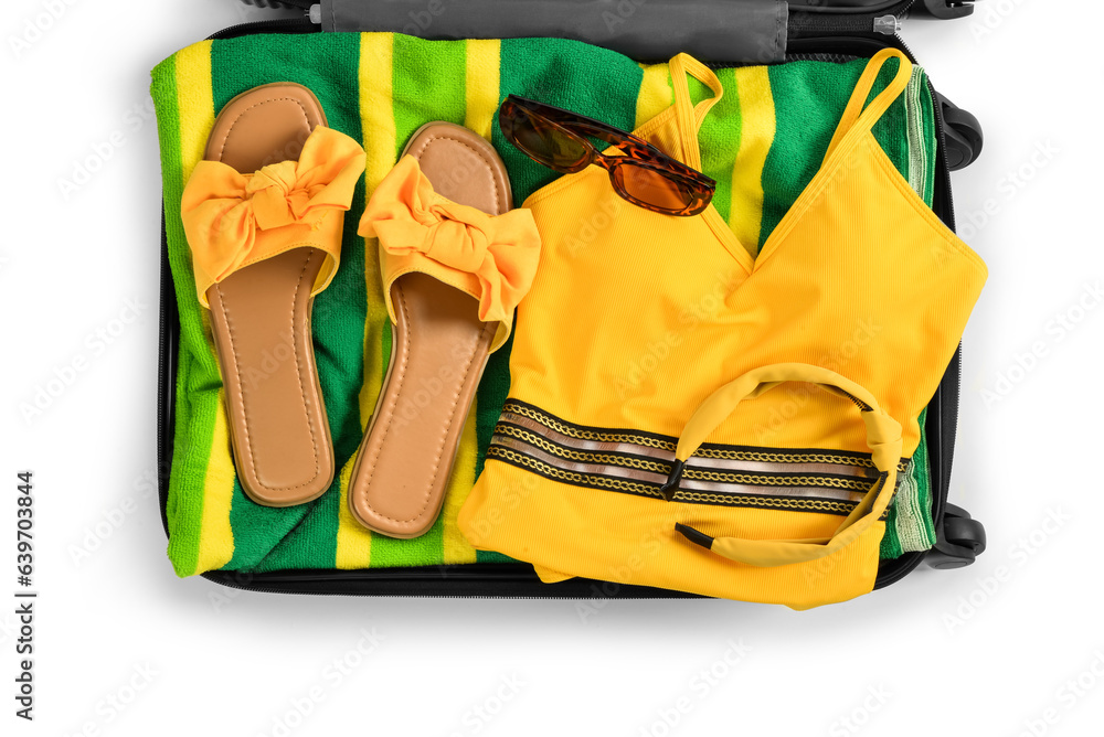 Suitcase with stylish beach accessories on white background, closeup