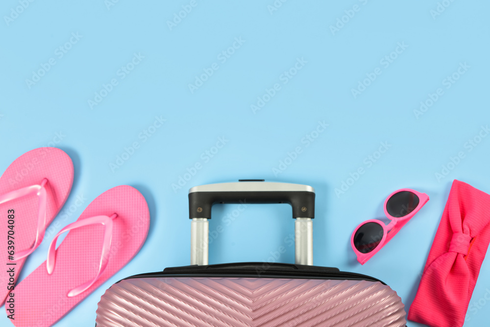 Set of beach accessories and suitcase on color background