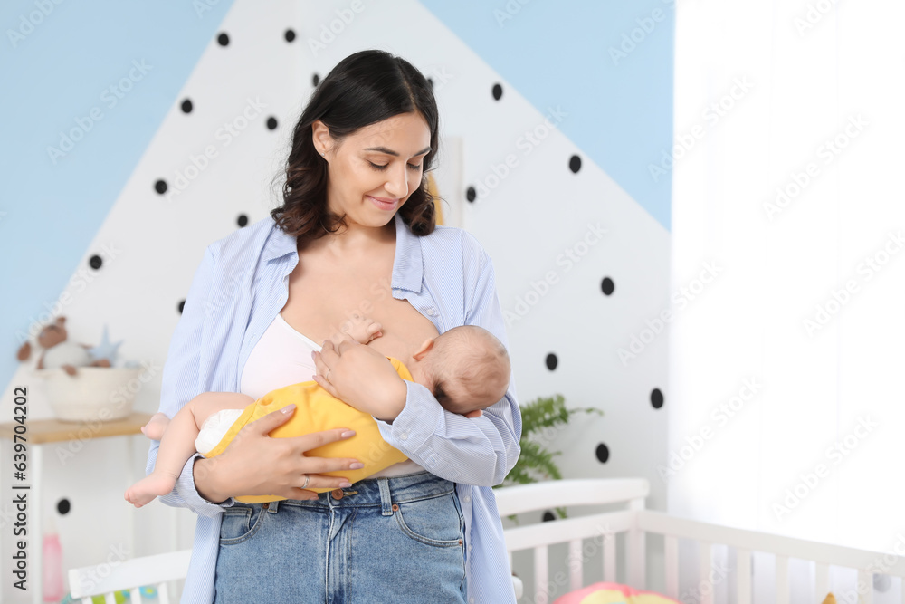 Young woman breastfeeding her baby in bedroom