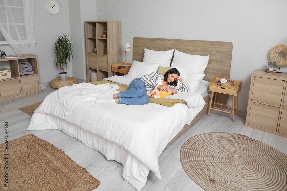 Young woman breastfeeding her baby in bedroom