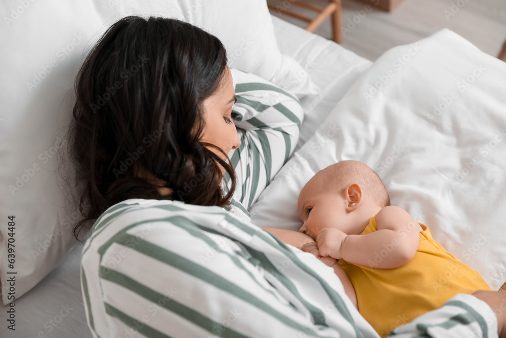 Young woman breastfeeding her baby in bedroom, closeup