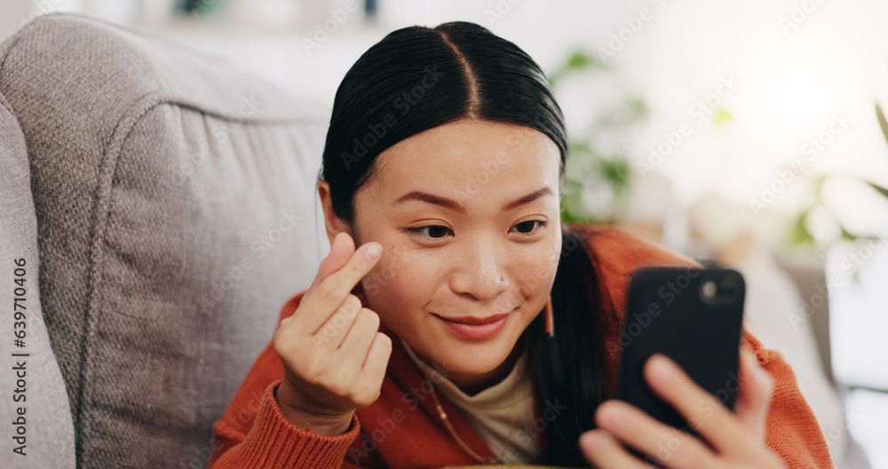 Asian woman, selfie and lying on sofa with heart sign and love for profile picture, vlog or social m