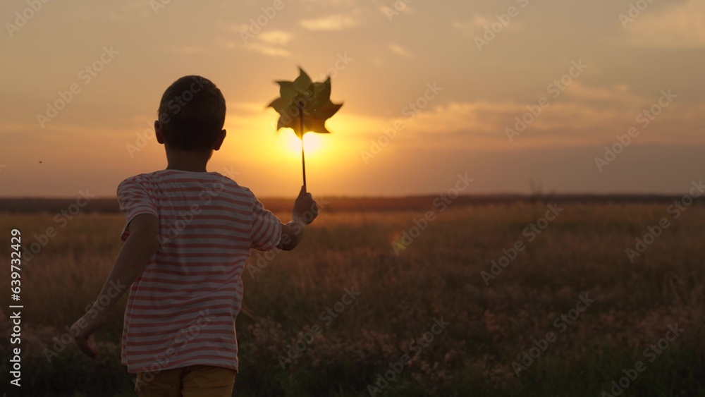 Active kid plays with toy pinwheel outdoors in spring park in sunshine. Childhood, children. Little 