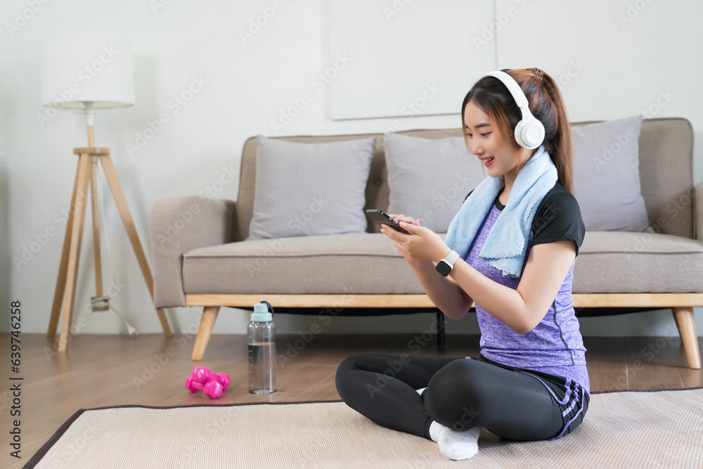 Young asian woman wear headphone to surfing internet and listens music on smartphone after exercise