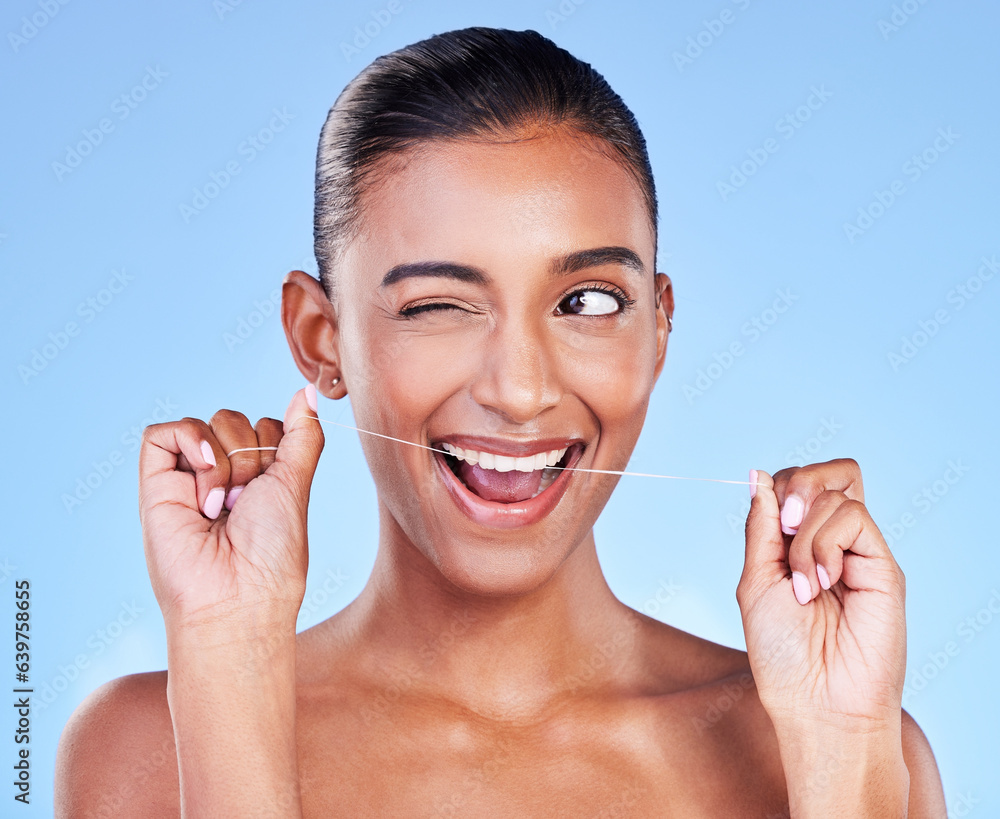 Woman, wink and floss teeth in studio for healthy dental care, gum gingivitis and plaque on blue bac