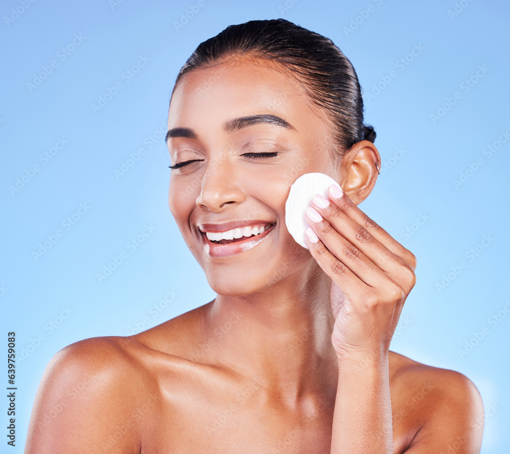 Woman, face and cotton pad for skincare, cosmetics and aesthetic shine on blue background in studio.