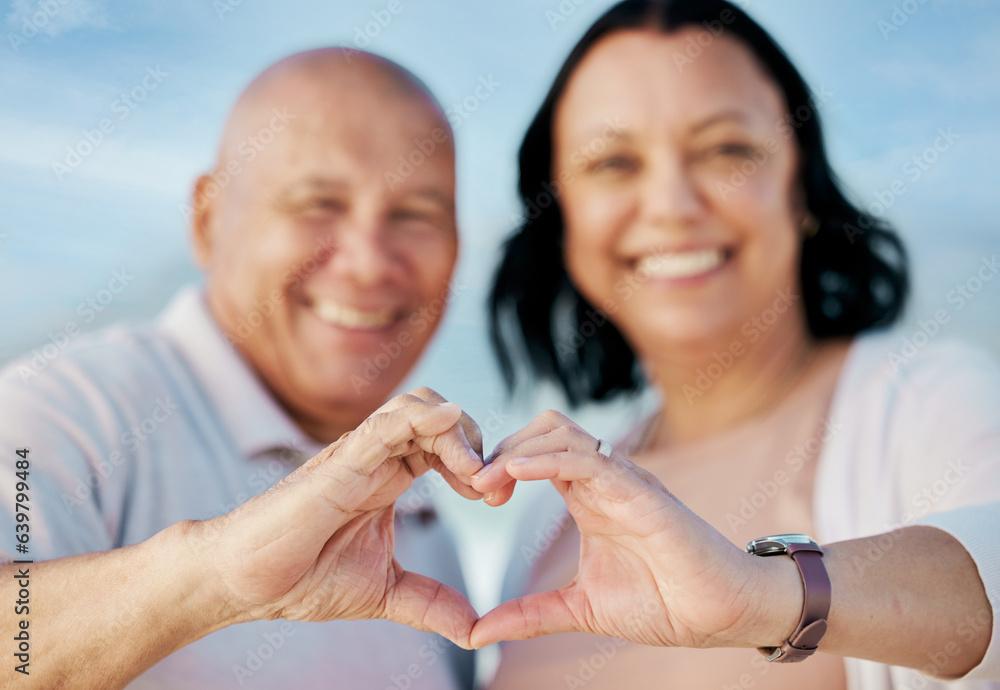 Heart shape, hands and mature couple at the beach on a romantic vacation, adventure or holiday. Smil