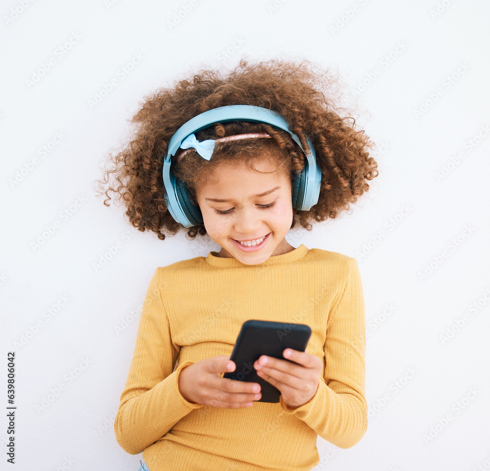 Girl kid, chat and smartphone, headphones and music with smile isolated on white background. Technol