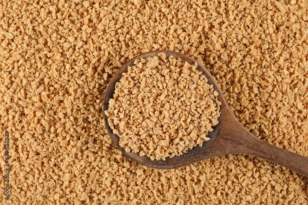 Soy flakes uncooked, soybean cereal in wooden spoon background and texture, top view