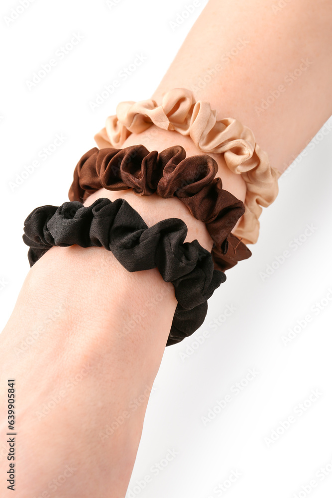 Female hand with stylish scrunchies on white background, closeup