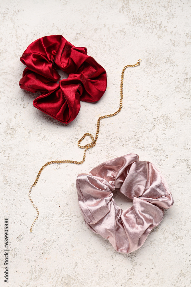 Silk scrunchies and necklace on light background